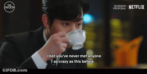 A Man In A Suit Drinking From A White Cup With A Netflix Logo In The Background GIF