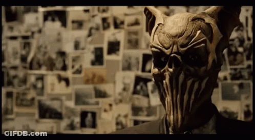 A Man In A Suit Has A Mask On His Face GIF