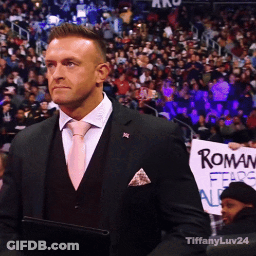 A Man In A Suit Holding A Sign That Says Roman Fears All GIF