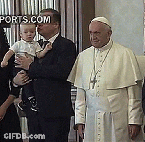 A Man In A Suit Holds A Baby In Front Of A Man In A White Robe With The Words Ports.com On The Bottom Right GIF
