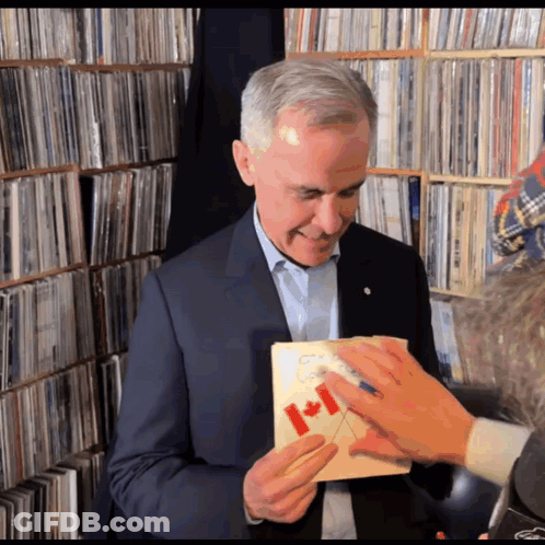 A Man In A Suit Holds A Canadian Flag In His Hand GIF