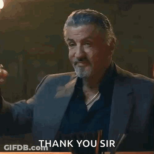 A Man In A Suit Holds A Glass Of Whiskey And Says Thank You Sir GIF