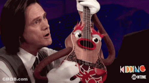 A Man In A Suit Holds A Guitar With A Crab Face On It GIF