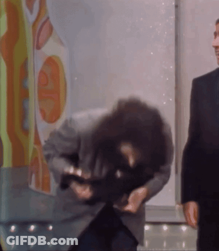 A Man In A Suit Holds A Gun In His Hand GIF