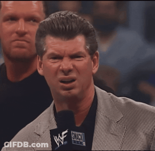A Man In A Suit Holds A Microphone That Says WWE On It GIF