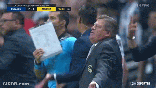 A Man In A Suit Holds A Piece Of Paper In Front Of A Fox Deportes Sign GIF