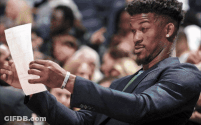 A Man In A Suit Holds A Piece Of Paper In His Hand GIF
