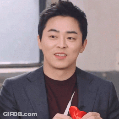 A Man In A Suit Holds A Red Heart In His Hands GIF