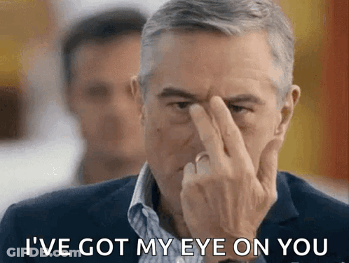 A Man In A Suit Holds His Finger To His Forehead And Says I 'Ve Got My Eye On You GIF