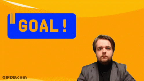 A Man In A Suit Holds His Fist Up In Front Of A Blue Sign That Says Goal GIF