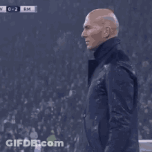 A Man In A Suit Holds His Hand To His Head GIF