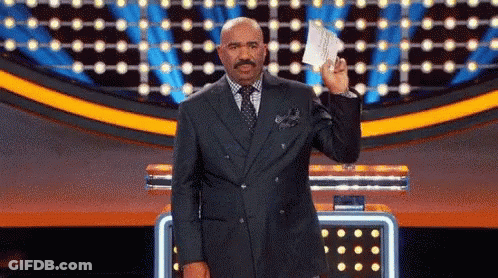 A Man In A Suit Holds Up A Piece Of Paper GIF