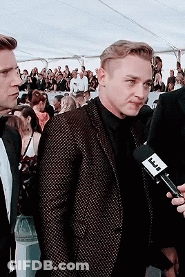 A Man In A Suit Is Being Interviewed By A Man Holding A Microphone With A Label That Says Tnt GIF