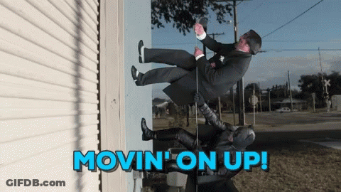 A Man In A Suit Is Being Lifted Up By A Batman GIF