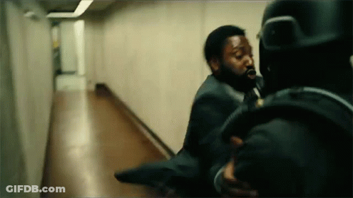 A Man In A Suit Is Being Thrown By Another Man In A Hallway . GIF