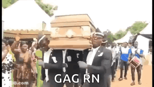 A Man In A Suit Is Carrying A Coffin In A Crowd Of People . GIF