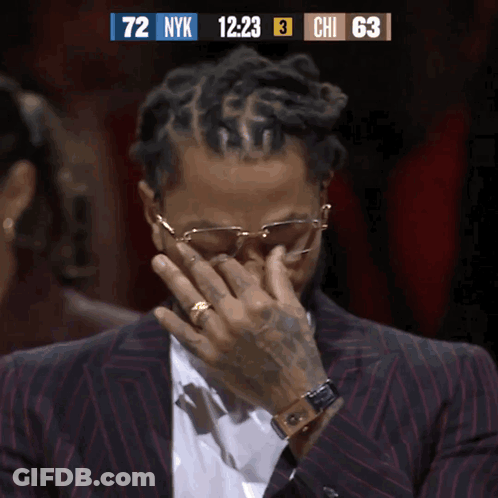 A Man In A Suit Is Covering His Face While Watching A Basketball Game GIF