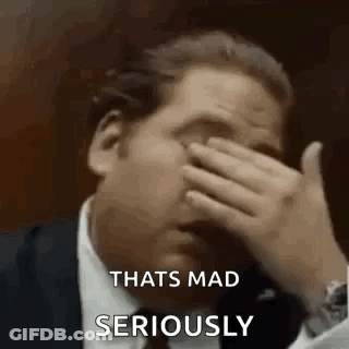 A Man In A Suit Is Covering His Face With His Hand And Saying `` That 'S Mad Seriously '' . GIF
