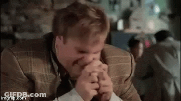 A Man In A Suit Is Covering His Mouth With His Hands . GIF
