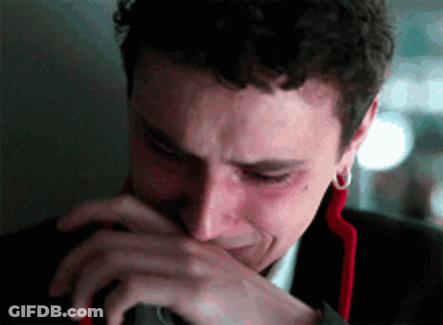 A Man In A Suit Is Crying And Covering His Mouth With His Hand . GIF