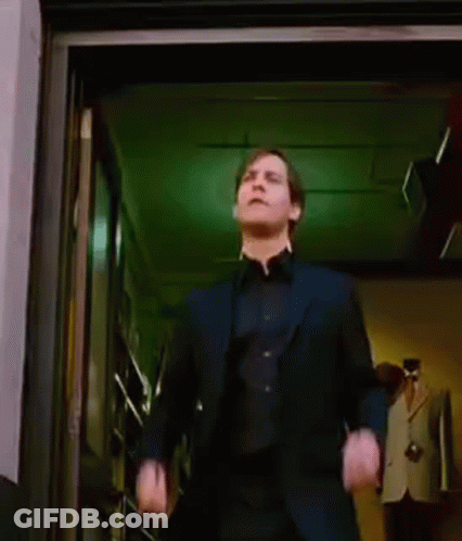 A Man In A Suit Is Dancing In A Doorway While A Woman Stands Behind Him . GIF