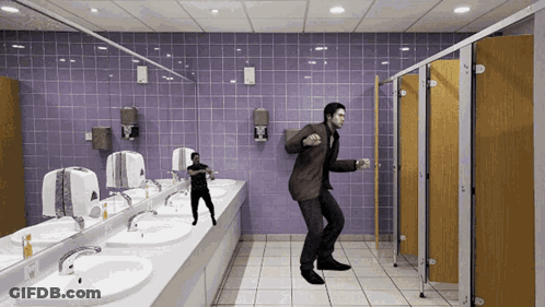 A Man In A Suit Is Dancing In A Public Bathroom GIF