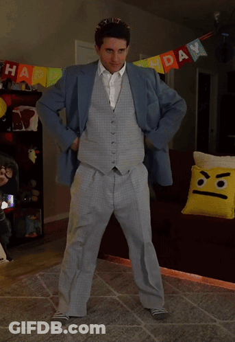 A Man In A Suit Is Dancing In Front Of A Birthday Banner GIF