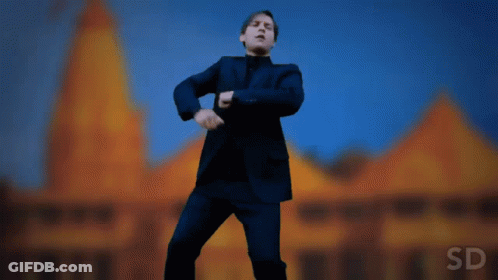 A Man In A Suit Is Dancing In Front Of A Building With The Letters Sd On The Bottom GIF