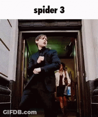 A Man In A Suit Is Dancing In Front Of A Door . GIF