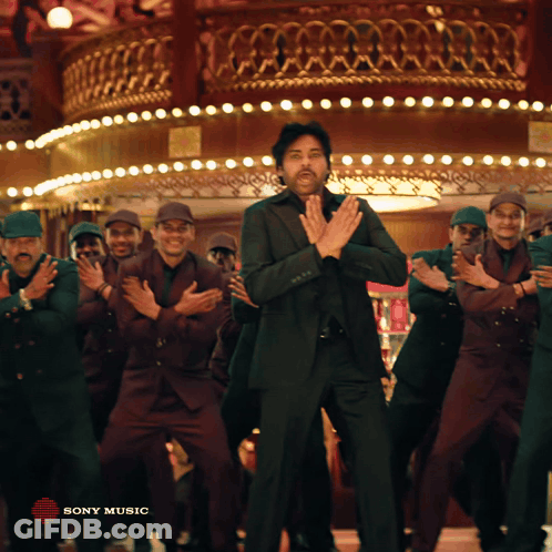 A Man In A Suit Is Dancing In Front Of A Group Of Men With Sony Music Written In The Corner GIF
