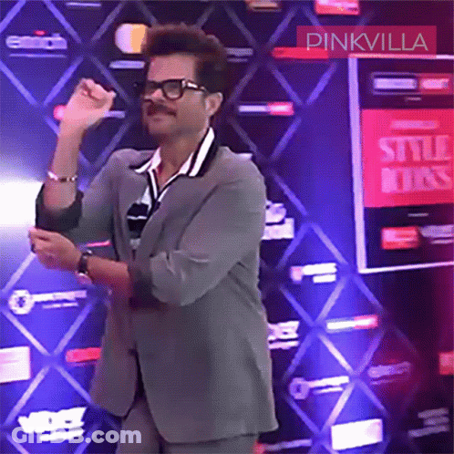 A Man In A Suit Is Dancing In Front Of A Pinkvilla Sign GIF