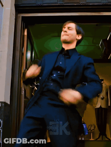 A Man In A Suit Is Dancing In Front Of A Store With The Letters Bk On The Bottom GIF
