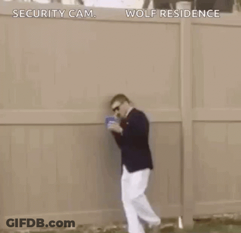 A Man In A Suit Is Dancing In The Grass While Holding A Blue Cup . GIF