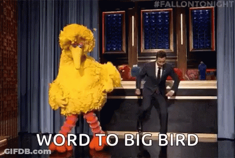 A Man In A Suit Is Dancing Next To A Big Bird Costume . GIF
