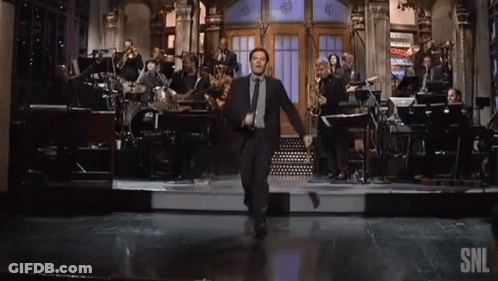 A Man In A Suit Is Dancing On A Stage With A Snl Logo In The Corner GIF