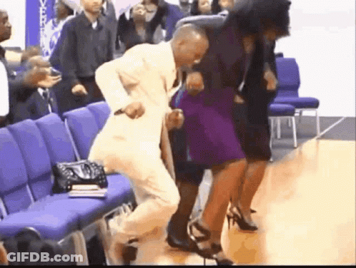 A Man In A Suit Is Dancing With A Woman In A Purple Dress In A Church . GIF