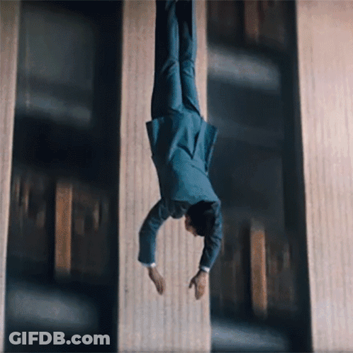 A Man In A Suit Is Doing A Handstand In The Air GIF