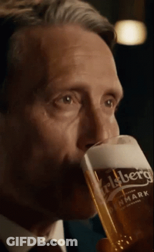 A Man In A Suit Is Drinking From A Carlsberg Glass GIF