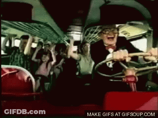 A Man In A Suit Is Driving A Bus With A Crowd Of People On It . GIF