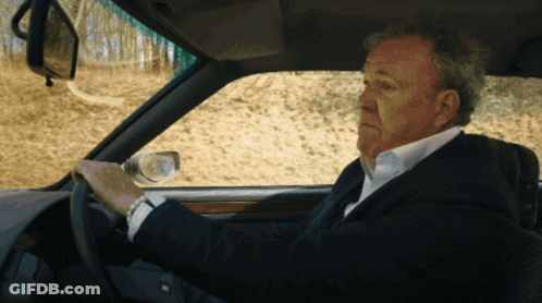 A Man In A Suit Is Driving A Car And Looking At His Watch GIF