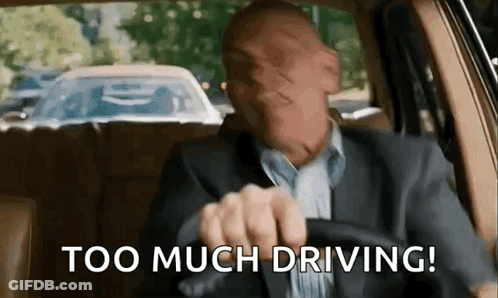 A Man In A Suit Is Driving A Car And Making A Face . GIF