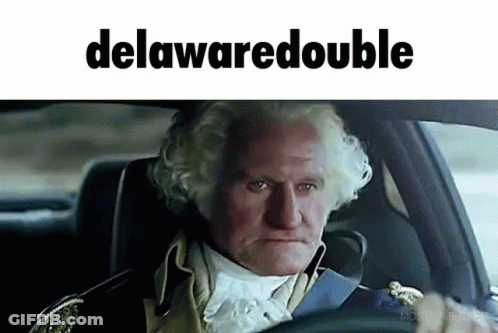 A Man In A Suit Is Driving A Car With The Word Delawaredouble On The Bottom GIF
