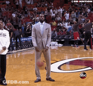 A Man In A Suit Is Holding A Basketball On A Basketball Court With A Abc Logo In The Background GIF