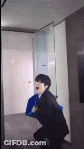 A Man In A Suit Is Holding A Blue Umbrella While Standing In A Hallway . GIF