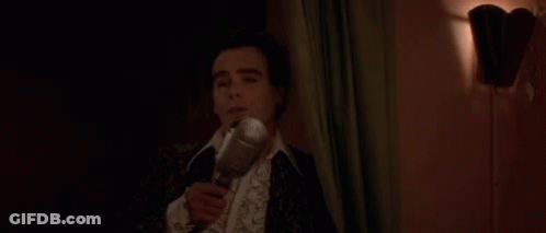 A Man In A Suit Is Holding A Bottle Of Wine In His Hand . GIF