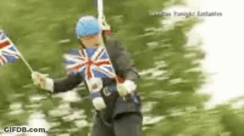 A Man In A Suit Is Holding A British Flag In His Hands . GIF