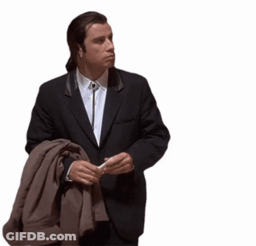 A Man In A Suit Is Holding A Brown Jacket GIF