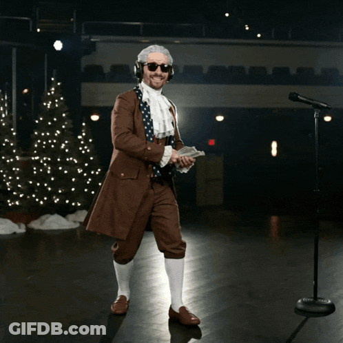 A Man In A Suit Is Holding A Bunch Of Money In Front Of A Christmas Tree GIF