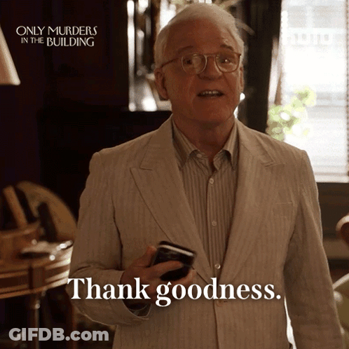 A Man In A Suit Is Holding A Cell Phone And Saying Thank Goodness GIF
