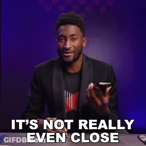 A Man In A Suit Is Holding A Cell Phone With The Words It 'S Not Really Even Close Below Him GIF